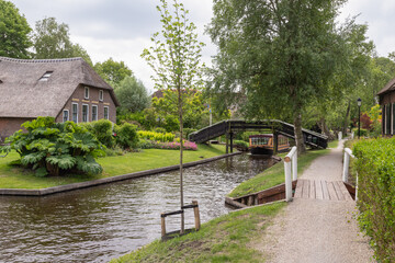 Rural village of Giethoorn with picturesque houses with thatched roofs and narrow wooden bridges.