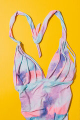 Multi-colored swimsuit on yellow background.