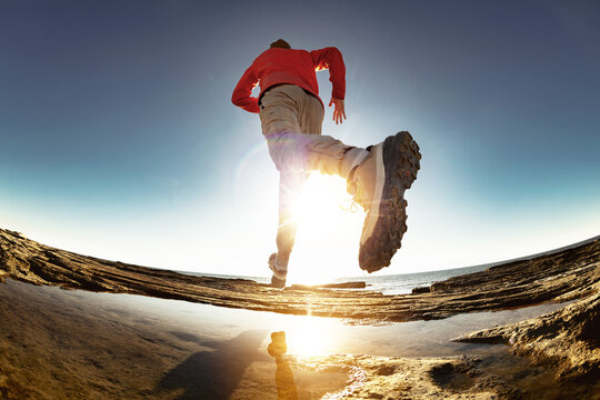 sporty man athlete run and jump over puddle at sunset. Close up photo of sportsman leg and shoe