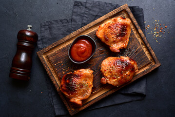 Roasted chicken thighs with ketchup. Top view with copy space.