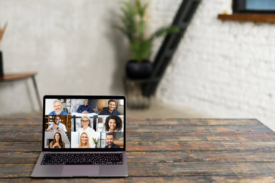 An open laptop on a rustic wooden table displays a virtual meeting with diverse faces on screen, symbolizing the new era of digital collaboration and remote work