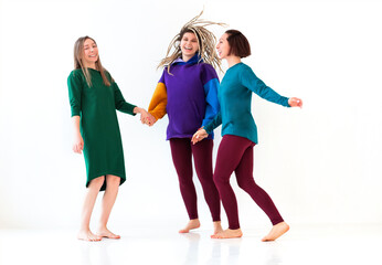 Three happy playful barefoot women of different age holding hands together, jumping and having fun