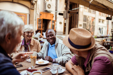 Diverse elderly tourist sitting in city outdoor cafe