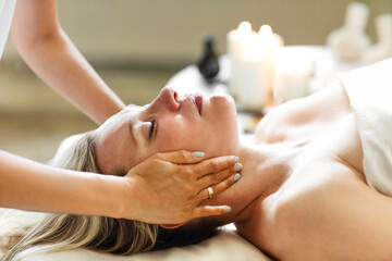 Obraz na płótnie Canvas Asian masseuse massaging face of client
