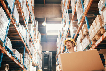 Young man carrying box in large warehouse