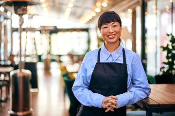 An Asian waitress smiling for the camera, dressed in her uniform.