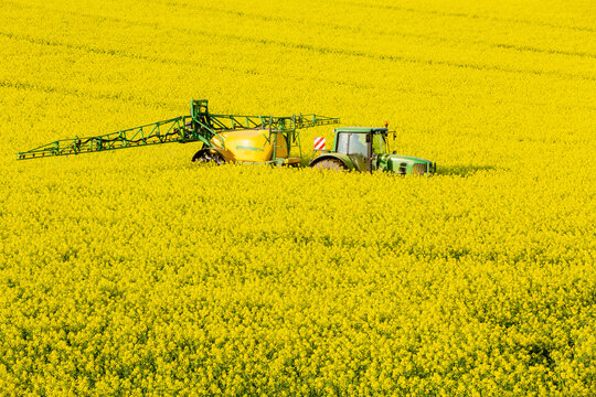 Farmer with John Deer tractor and agricultural sprayer in Canola Field, Germany, Lower Saxony, Editorial
