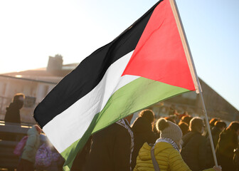 large Palestinian flag waving against the light during the pacifist demonstration with many people...