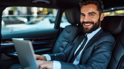 Handsome businessman working on laptop computer while sitting in luxury car.