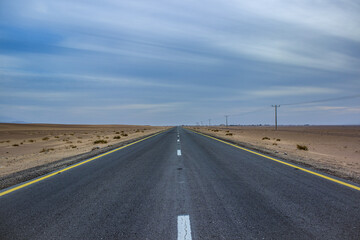 drive in desert on straight asphalt road idyllic simple wallpaper concept country side dramatic picture with cloudy weather and sand environment