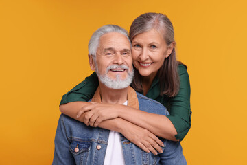 Portrait of affectionate senior couple on orange background