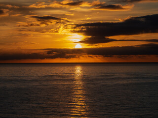 Calm sea with sunset sky and sun through the clouds over. Meditation ocean and sky background. Tranquil seascape. Horizon over the water