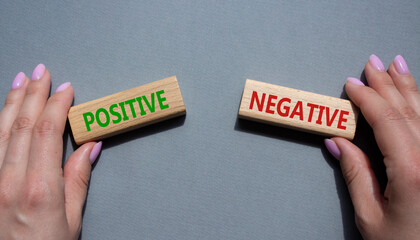 Positive or Negative symbol. Concept word Positive or Negative on wooden blocks. Businessman hand. Beautiful grey background. Business and Positive or Negative concept. Copy space