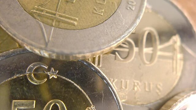 A macro shot of a 50 Kuruş coin with the camera panning from left to right, showing the fine lines and patterns of the currency. The coin is bimetallic, with a bronze center and a silver ring. 
