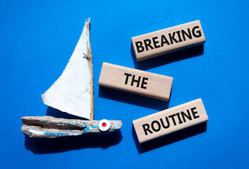Breaking the Routine week symbol. Concept words Breaking the Routine on wooden blocks. Beautiful blue background with boat. Business and Breaking the Routine concept. Copy space