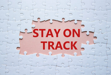 Stay on track symbol. Concept words Stay on track on white puzzle. Beautiful pink background. Business and Stay on track concept. Copy space.