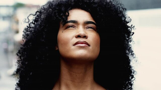 Young Spiritual African American woman looking up at sky BELIEVING and feeling the presence of a HIGHER POWER, belief and inspiration close-up face skyward