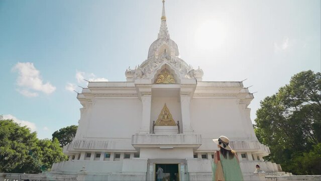 Rear view of tourist woman walking into Kanchanapisek Pagoda temple(White Pagada) in Khao Kho, Phetchabun, Thailand. Pay respects to the Buddha statues inside for good fortune