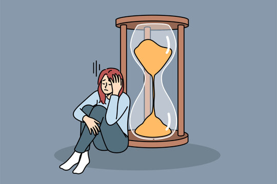 Woman is sad about strict deadlines sitting near large hourglass, and needs skills improve productivity. Concept lack of productivity causes stress in girl due to inability complete work on time - Powered by Adobe