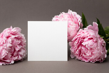 Blank square card mockup with fresh peony flowers, blank invitation, greeting or flyer card mock up
