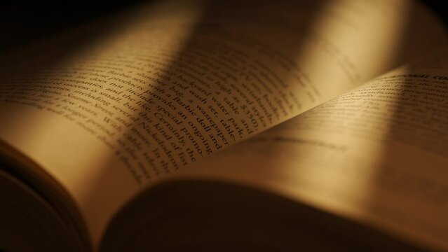 Close up studio shot of old retro hardcover book on dark background in warm light. Beautiful old book with light moving on surface