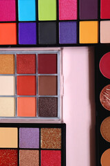 Various colorful eyeshadow palettes on bright pink background. Flat lay.