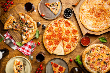 Family or friends pizza party. Flat-lay of different types of pizza and red wine over rustic wooden...
