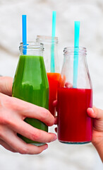 Family of three clinking glasses with fresh multicolored juice