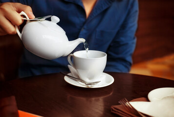Man pouring tea into a white china tea cup
