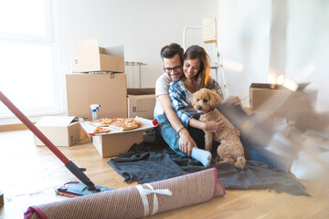 Young beautiful couple moving to a new apartment with their dog together.