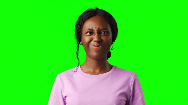 Young African woman making silly faces against green background