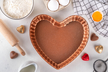 Sweet Valentine day baking background. Ingredient for making Valentine cookies, cakes, dessert with chocolates, sugar sprinkles, baking ingredients, flour, egg, milk, rolling pin top view 