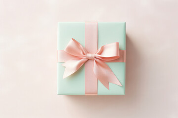A mint green gift box with a delicate pink satin ribbon, captured from above on a white background. - Powered by Adobe