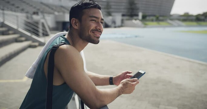 Happy man, fitness and phone typing on break for communication or social media at stadium. Active male person or runner smile in relax or rest on mobile smartphone for online chatting, texting or app