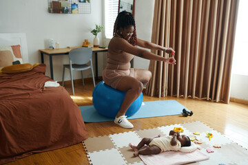 Happy mother of newborn baby exercising at home