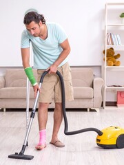 Young injured man cleaning the house