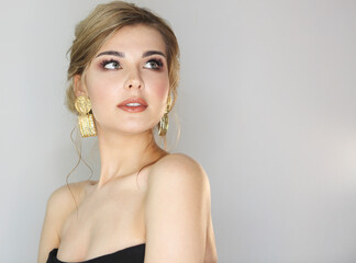 Fototapeta premium Portrait of the woman with fashion hairstyle and makeup wearing big golden earrings