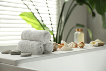Fototapeta na wymiar Bath tray with spa products and towels on tub in bathroom