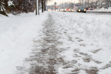 Winter road with melting from salt snow. Close up of sidewalk with slush on snowy day