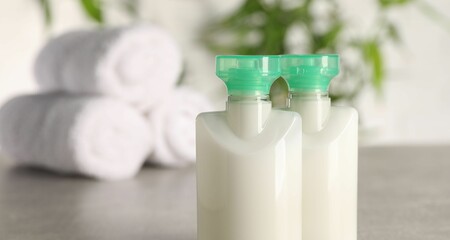 Mini bottles of cosmetic products against blurred background, closeup. Space for text