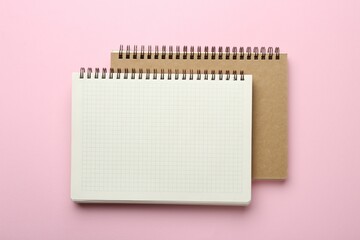 Two notebooks on pink background, top view