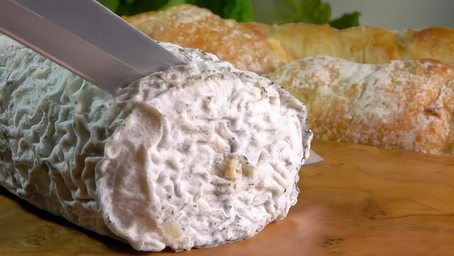Natural goat cheese with gray mold is cut with a knife