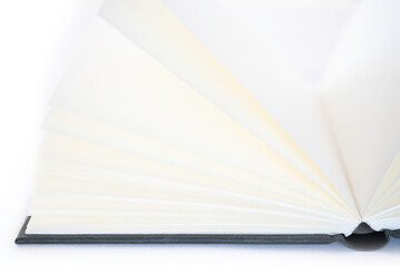 Open book with white blank pages and a black linen cover, isolated on a white background. Very narrow depth of field