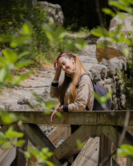 Backpacking woman leaning on a bridge, taking off sunglasses