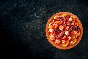 Pulpo a la gallega, Spanish octopus meal, Galician dish, overhead flat lay shot on a black...
