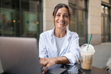 Contented cute woman sitting at the table in a street cafe