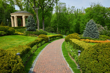 Trimmed green bushes form a labyrinth along tiled pathways in the park,