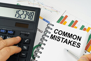 On the table there is a calculator, reports with graphs and a notepad with the inscription - Common Mistakes