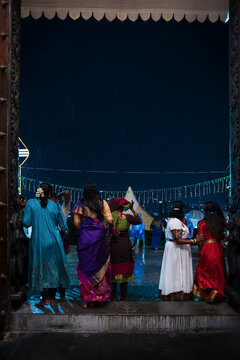 Women with Saris at the temple entrance waiting for rain to stop at Thaipusam in Penang, Malaysia