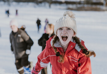 Girl in red snow suit running in the snow laughing and having fun with children behind her